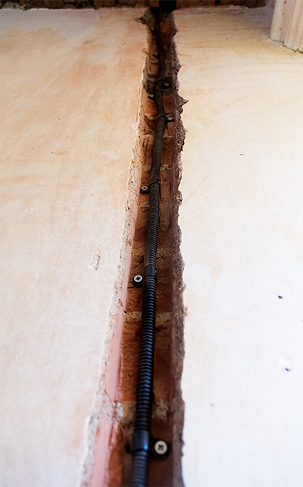 Electric cable conduit attached to wall